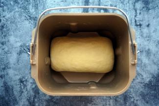 揉面程序完成后，点击暂停键，将面团取出，取出搅拌刀，然后将面团卷起，重新放入面包桶内，点击继续。