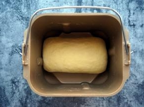 揉面程序完成后，点击暂停键，将面团取出，取出搅拌刀，然后将面团卷起，重新放入面包桶内，点击继续。