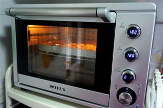 听到烤箱发出“嘀”的一声表示已经预热好，此时将曲奇放入中层烘烤。