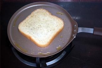 不粘锅放点油，然后放入面包片，两面都煎一煎，微微金黄即可。