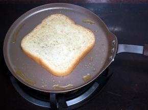 不粘锅放点油，然后放入面包片，两面都煎一煎，微微金黄即可。