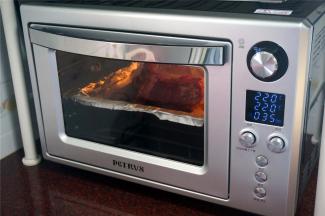 烤箱选择上下大温幅功能，温度为220度，时间35分钟，启动。烤盘垫上锡纸，摆入腌制好的排骨，放入预热好的烤箱中层，开始烘烤。