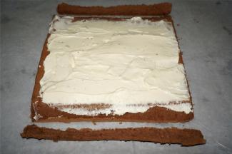 冷却过程，将150克的淡奶油加入15克的细砂糖打发至硬性发泡，抹在蛋糕体上。蛋糕体首尾斜切去少许边。