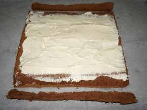 冷却过程，将150克的淡奶油加入15克的细砂糖打发至硬性发泡，抹在蛋糕体上。蛋糕体首尾斜切去少许边。