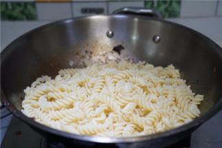 锅里留少许的食材，将煮好的意面下锅拌炒至挂味即可。