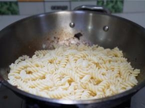 锅里留少许的食材，将煮好的意面下锅拌炒至挂味即可。