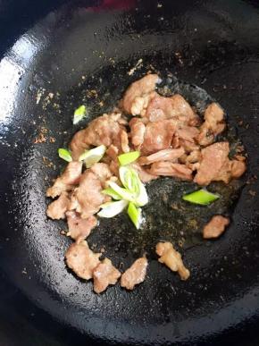 6、倒入葱花和豆瓣酱快速翻炒一下