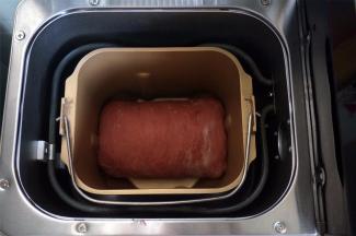 将面团卷起，放入面包机桶内。