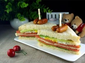 从底部到表层依次摆上吐司片、生菜、火腿片、芝士片、吐司片、火腿片、煎蛋、生菜、吐司片，然后用刀从对角将整体切成两份即可。