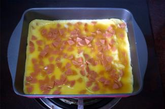 热锅下油，倒入火腿蛋液，煎熟，然后对半分成两份。