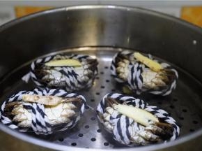 将刷好的闸蟹倒扣放在蒸格上，再放上姜片。蒸十分钟左右至蟹熟。