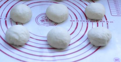 7、取出排气后，将面团分割成90g左右的6块，  然后滚圆 盖上保鲜膜 松弛10分钟，这个必须做，否则擀不开长度