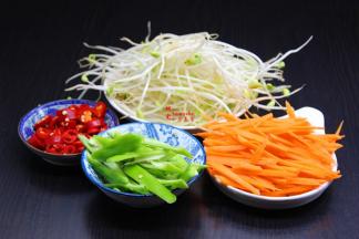 胡萝卜去皮洗净切丝，豆芽洗净沥干水，红辣椒青辣椒分别洗净切好；