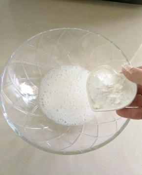 把蛋清，白醋倒入碗中。用打蛋器打出大气泡，加入一半的糖粉。