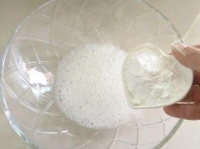 把蛋清，白醋倒入碗中。用打蛋器打出大气泡，加入一半的糖粉。