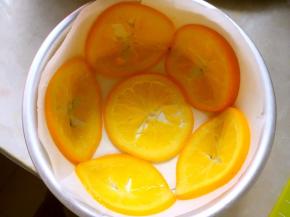 为了方便脱模，模具底下铺油纸，侧面也围一圈油纸，将橙片滤干汤汁，如图铺在模具底部及边缘