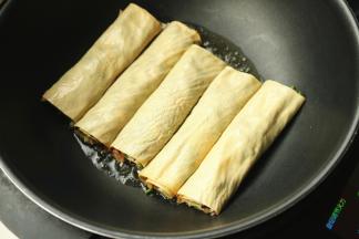 炒锅放油，下入豆皮肉卷开始煎制。