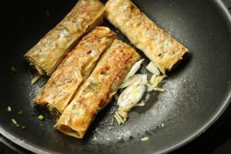 煎至两面金黄，推到一边，下入一些葱丝炒香。