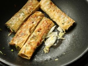 煎至两面金黄，推到一边，下入一些葱丝炒香。