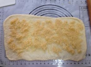 发酵好的面团，取出排气，盖上保鲜膜静置15分钟。然后将面团擀成长方形，一边长边擀簿，辅上椰蓉馅