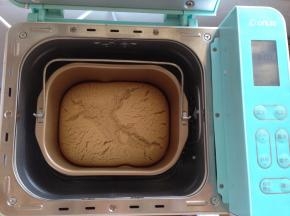 这是做好的蛋糕。戴上隔热手套，将面包桶提出，在桌面上震一下