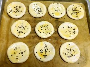 收口朝下放在烤盘上，烤箱预热180度，蛋液打散，均匀的刷在表层，之后撒点黑芝麻