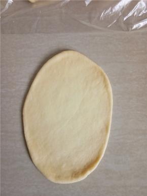 取一个小面团拍扁排气，擀成长椭圆形。