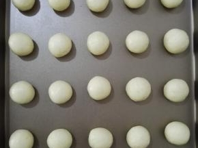 6、将面团分成20个均等的小面团，用手揉成圆形，置于烤盘中，烤箱预热上下火180度。