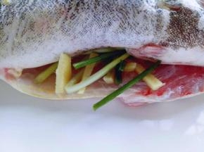 将葱段，姜丝放进鱼的肚子里。