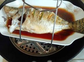 蒸好的桂鱼，用夹子将盘子夹出，注意烫手。
蒸好的鱼会有很多汤汁，将汤汁倒出，再换个干净的鱼盘。(不换鱼盘也可以)