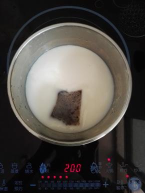 5、放电磁炉上中火加热烧开，用小勺搅拌一下，使牛奶受热均匀。