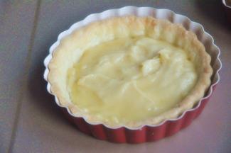 塔皮微温时，将杏仁奶油馅均匀涂抹在塔皮上。