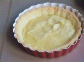 塔皮微温时，将杏仁奶油馅均匀涂抹在塔皮上。