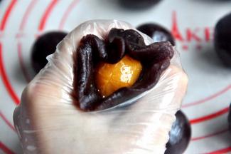 用豆沙把蛋黄包住，搓成圆球。