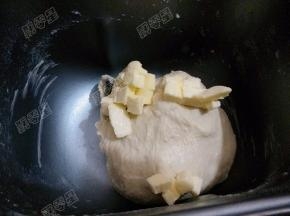 主料中除黄油外的所有材料放入面包桶，启动发面团程序揉面15分钟，面团形成面筋网络可以拉出粗膜，放入切成小块已经软化的黄油