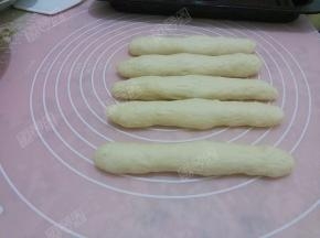 取一个剂子擀成长舌形，从上部向下卷起，接口处捏紧