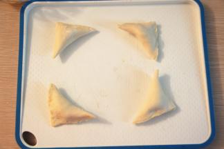 把榴莲果泥放在飞饼皮中央，饼皮斜角对折，包紧，取一把叉子轻轻压花边；