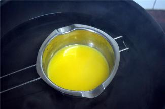 熬糖浆的时候，烧一锅热水，同时隔水融化黄油，备用。去皮花生也可以放入烤箱烤几分钟，温热备用。