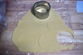 用一个比六连杯模具上口直径大3厘米的圆形饼干模具印出6片大圆面片。（没有模具的可以取一小块面团，捏成圆形薄片即可）
