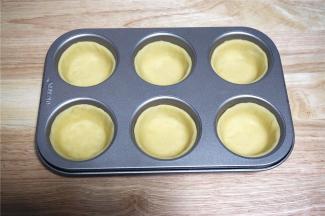 将大圆面片分别放入到六连杯模具中，用手压紧四周以及底部，不要留有空气。