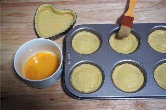 将之前剩余下来的面片揉合后重新擀开，然后用一个跟模具上口直径等大的圆形饼干模印出小圆片，盖在馅料上，形成密封的盒子。然后用叉子在顶部划上格子花纹，并刷上全蛋液。（剩余的面团我用了一个心形派模消耗掉，做一个没有馅料的派饼。）