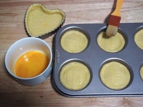 将之前剩余下来的面片揉合后重新擀开，然后用一个跟模具上口直径等大的圆形饼干模印出小圆片，盖在馅料上，形成密封的盒子。然后用叉子在顶部划上格子花纹，并刷上全蛋液。（剩余的面团我用了一个心形派模消耗掉，做一个没有馅料的派饼。）