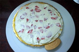 取一片班戟皮放在蛋糕底托上，然后挤上一圈圈的淡奶油，放入草莓粒，用刮刀抹平。