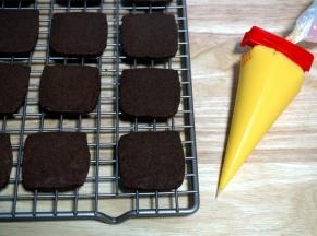 在一片饼干片上挤出巧克力馅料，然后压上另一片，馅料凝固后，饼干就做好了。