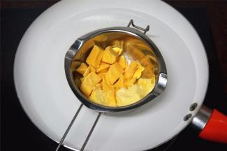 饼干冷却的过程，准备馅料。将巧克力和黄油切成小块，隔水融化后装入裱花袋里。