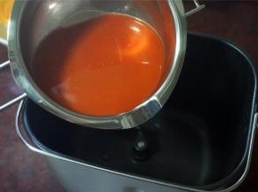 榨取新鲜的胡萝卜汁，取120毫升加入到面包机桶里。