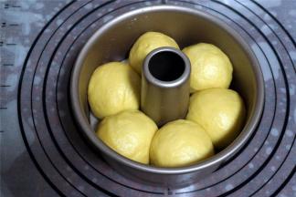 将面团平均分成6等份，揉圆，放入刷了烤盘油的6寸不粘中空模具中，盖上保鲜膜，放入烤箱中下层，启动烤箱发酵程序，发酵30分钟。