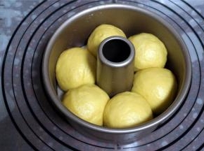 将面团平均分成6等份，揉圆，放入刷了烤盘油的6寸不粘中空模具中，盖上保鲜膜，放入烤箱中下层，启动烤箱发酵程序，发酵30分钟。