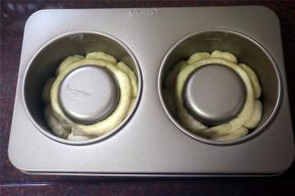 模具壁上刷烤盘油。将小圆面团排放入大堡模具中，剩下的面团揉成长条状，围在模具内则，如图。