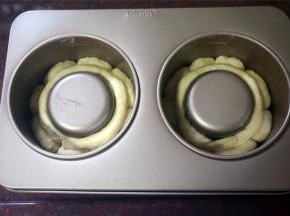 模具壁上刷烤盘油。将小圆面团排放入大堡模具中，剩下的面团揉成长条状，围在模具内则，如图。